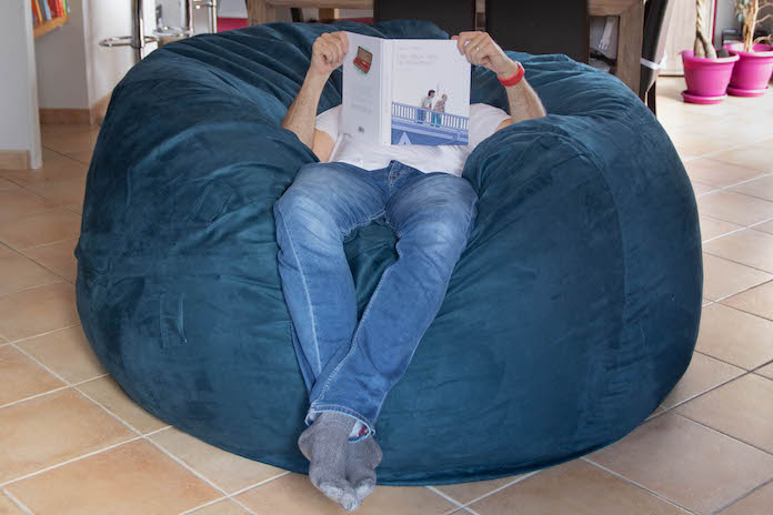 homme assis sur un pour et lisant un livre